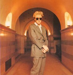 a man in a suit and sunglasses standing in a tunnel with his hands on his hips