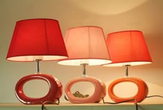 three lamps sitting on top of a table next to each other and one red lamp