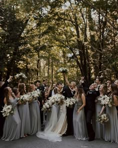 a group of people standing around each other in front of trees with flowers on their heads