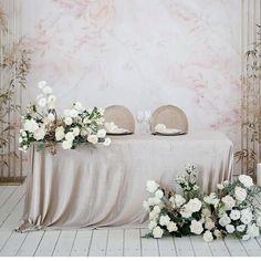 the table is set up with white flowers and place settings for two people to sit at