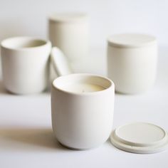 three white cups sitting next to each other on top of a table with one cup in the middle