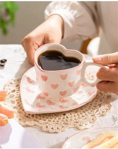 a woman holding a cup of coffee on top of a white saucer and plate