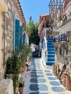 an alley way with blue steps and potted plants on either side, surrounded by stone buildings