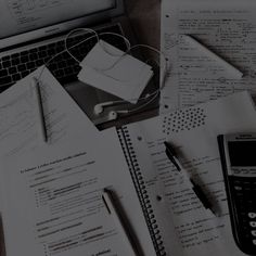 an open laptop computer sitting on top of a desk next to papers and calculator