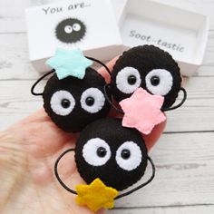 three small black balls with googly eyes and a star on their fingers are shown