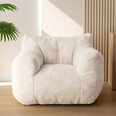 a white chair sitting on top of a wooden floor next to a potted plant