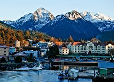 the mountains are covered in snow and some boats are parked on the water near them