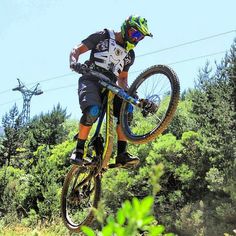 a person on a bike doing a trick in the air over some grass and trees