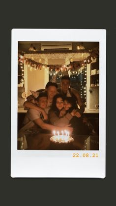 a group of people standing in front of a cake with lit candles on top of it