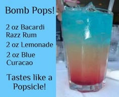 a blue and red drink sitting on top of a table next to a sign that says bomb pops