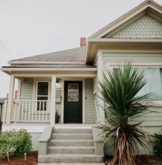 a house with a palm tree in front of it and stairs leading up to the door