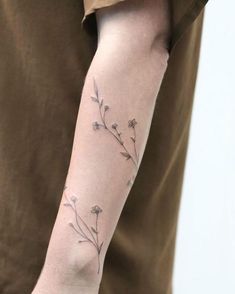 a person with a tattoo on their arm that has flowers growing out of the side