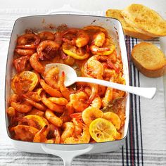 a white dish filled with shrimp next to bread