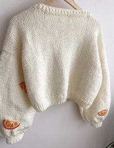 a white sweater hanging on a wooden hanger