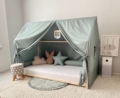 a child's bed with a tent on the top and pillows in front of it