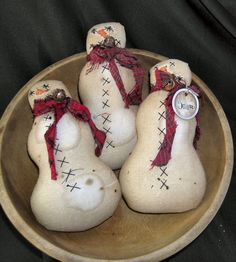 three snowmen are sitting in a bowl with red ribbon around their necks and feet