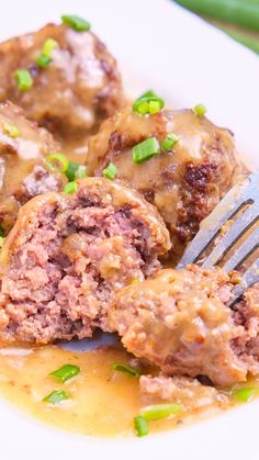 meatballs and gravy on a white plate with a fork in the middle