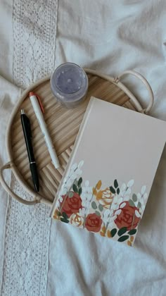 an open notebook sitting on top of a bed next to a pen and ink pot