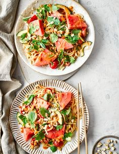 two plates with food on them next to silverware and spoons, one has watermelon