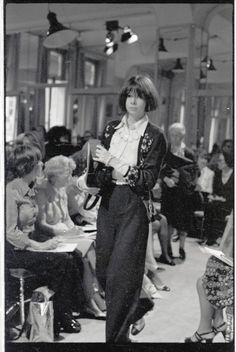 a black and white photo of a woman standing in front of a group of people