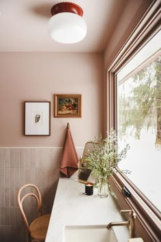 a bathroom with pink walls and white counter tops next to a large window that looks out onto the woods