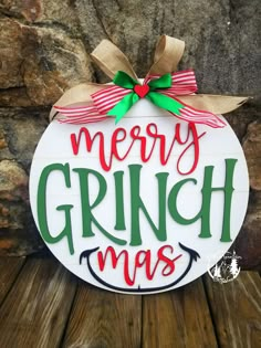 a merry grinmas ornament hanging on a wooden fence with a bow around it