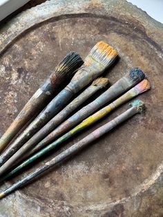 five paint brushes sitting on top of a dirty surface