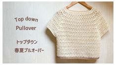 the top down pullover is crocheted in white yarn and sits on a wooden hanger