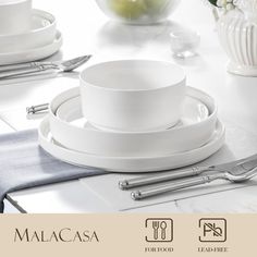 a table set with white dishes and silverware