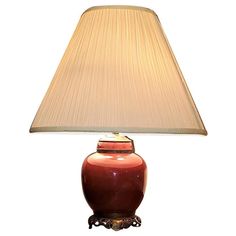 a red lamp with a beige shade on it's base and a white background