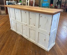 an old white kitchen island with wood top on the floor in a room filled with furniture