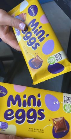 two boxes of mini eggs are being held by someone's hand