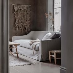 a living room with a white couch and wooden table next to a large open window