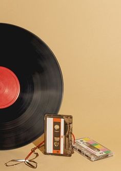 an old record player, tape recorder and earphones on a beige background with a red disc in the center