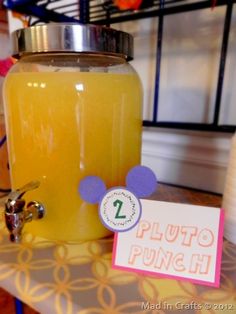 a table topped with a mason jar filled with liquid and a sign that says pluto punch