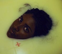 a woman laying in a bathtub filled with water and looking up at the camera