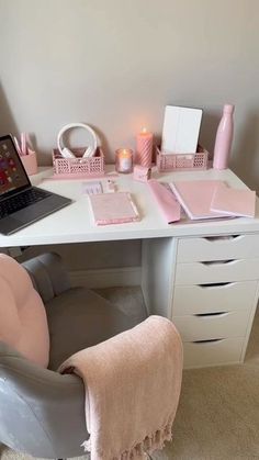 a white desk topped with a laptop computer sitting next to a pink chair and table