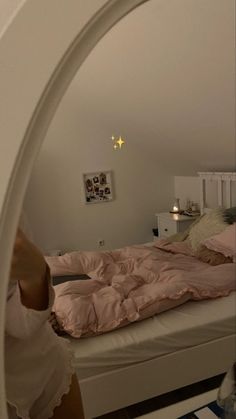 a woman taking a selfie in front of her bed with pink sheets and pillows