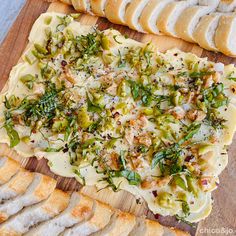 an assortment of breads and other food items on a wooden cutting board with cheese