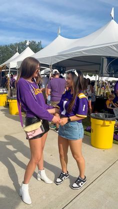 two young women shaking hands in front of tents