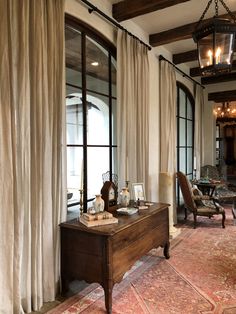 a living room filled with furniture next to a window covered in white curtained drapes