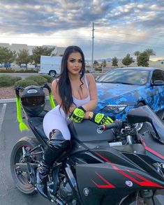 a woman sitting on top of a motorcycle in a parking lot