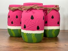 three pink mason jars with watermelon painted on them