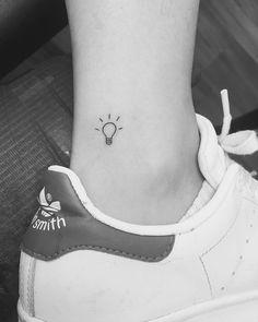 a black and white photo of a lightbulb tattoo on the side of a woman's ankle