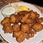 fried food on a white plate with dipping sauce and lemon wedges next to it