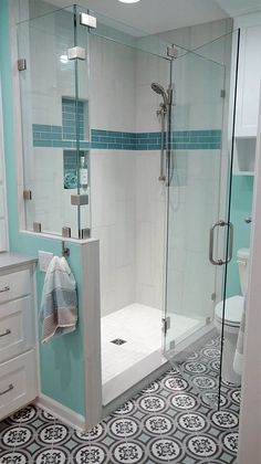 a bathroom with blue and white tiles on the floor, shower stall and sink area