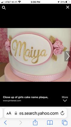 a white cake with pink flowers and gold lettering on the top that says maiya