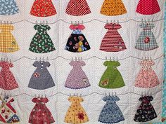 a quilted wall hanging with many different dresses on it