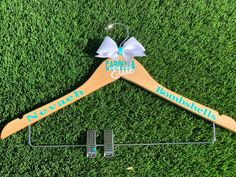 a personalized wooden hanger with a name on it sitting in the grass next to a pair of scissors