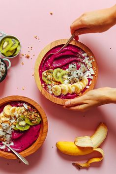 two bowls filled with different types of food on top of a pink surface next to bananas